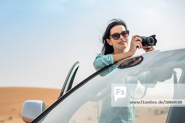 Weibliche Touristin fotografiert über einem Geländewagen in der Wüste  Dubai  Vereinigte Arabische Emirate