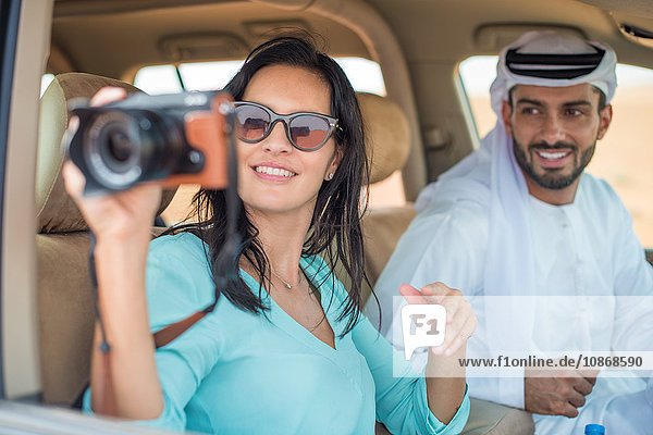 Female tourist in off road vehicle in desert taking photographs  Dubai  United Arab Emirates