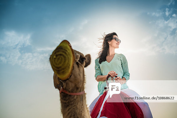Niedrigwinkelaufnahme eines weiblichen Touristen auf einem Kamel in der Wüste  Dubai  Vereinigte Arabische Emirate