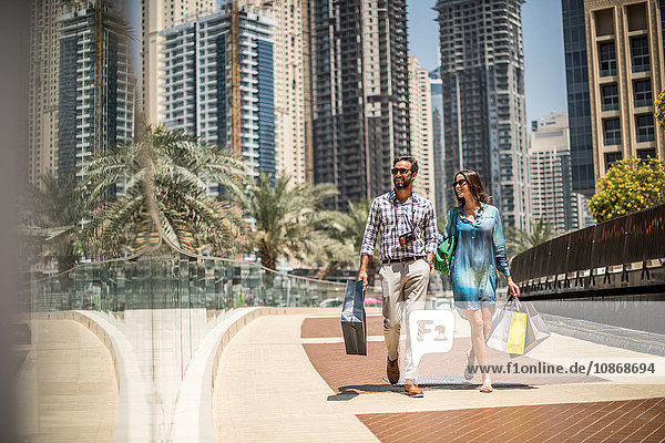 Touristenpaar schlendert mit Einkaufstaschen auf dem Gehsteig  Dubai  Vereinigte Arabische Emirate