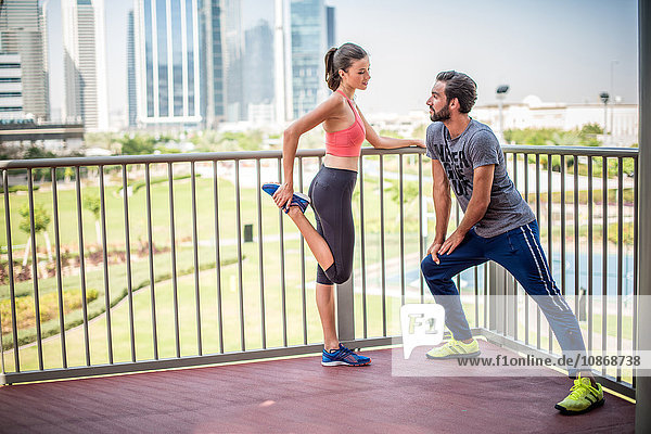 Ehepaar beim Stretch-Aufwärmtraining auf dem Balkon  Dubai  Vereinigte Arabische Emirate