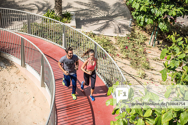 High angle view of running couple running up footbridge Dubai United Arab Emirates