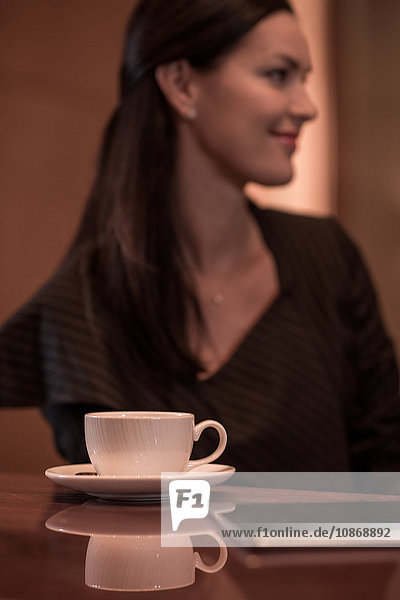 Geschäftsfrau sitzt an der Hotelbar mit Kaffee und digitalem Tablett