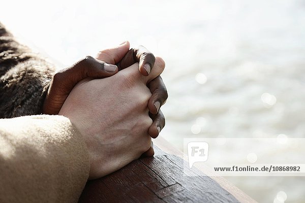 Multi ethnic couple outdoors  holding hands  close-up