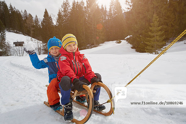 Junge und Bruder werden im Schnee auf einem Schlitten gezogen  Elmau  Bayern  Deutschland