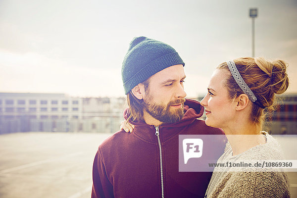 Mid adult couple gazing at each other on rooftop parking lot
