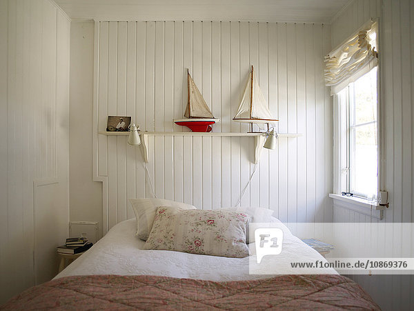 Schlafzimmer mit weißer Holzverkleidung und Bett