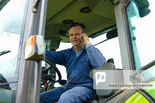 Farmer talking in tractor on smartphone