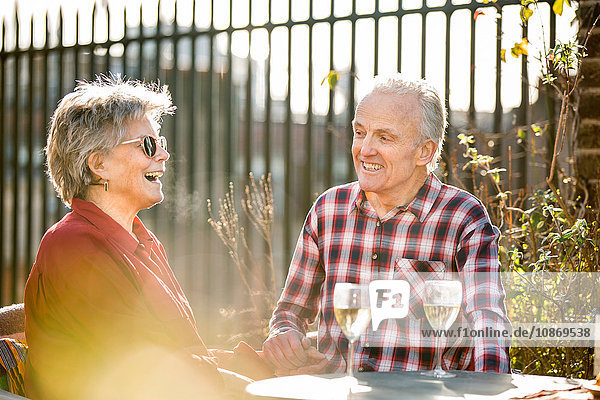 Älteres Ehepaar auf dem Dachgarten beim Plaudern und Entspannen mit Weißwein