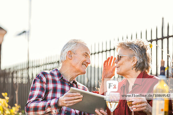 Älteres Ehepaar auf dem Dachgarten der Stadt mit digitalem Tablet