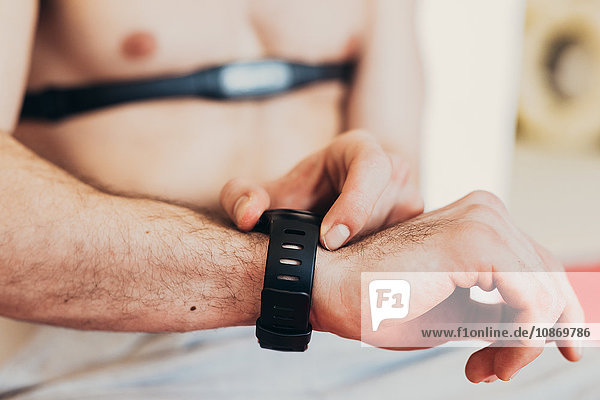 Mann trägt Herzfrequenzmessgerät an Brustkorb und überprüft Armbanduhr