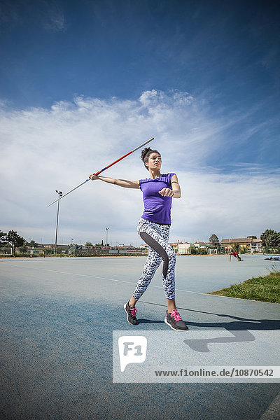 Young woman throwing javelin in sports ground