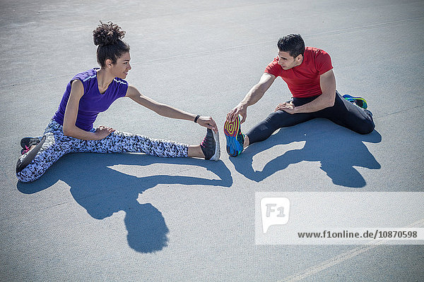 Junger Mann und Frau trainieren  Zehen auf Asphalt berühren