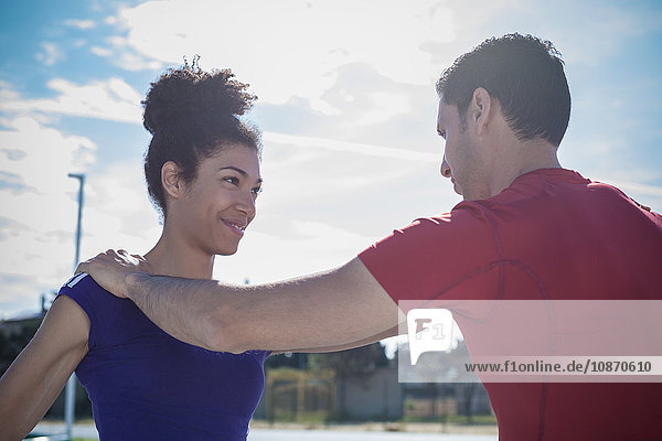 Mann unterrichtet junge Frau beim Training in Sportanlage