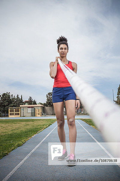 Portrait of young female pole vaulter concentrating at sport facility