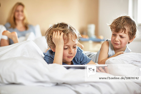 Boys on parents bed using digital tablet