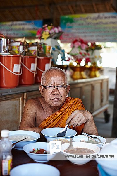 Buddhist monk eating Damnoen Saduak Market Thailand