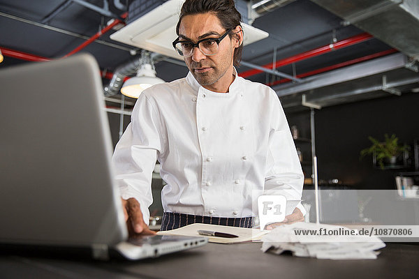 Chef in restaurant using laptop