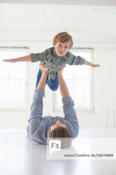 Father lying on floor holding up son