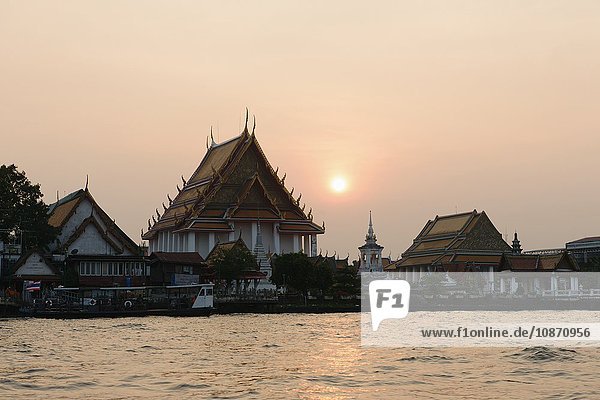 Chao Phraya und Tempel bei Sonnenuntergang Bangkok Thailand