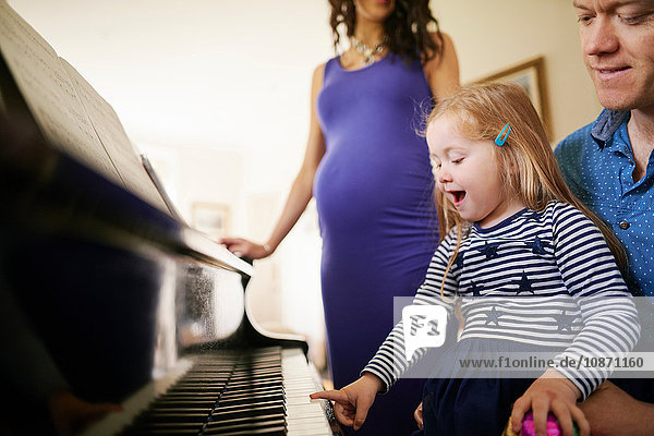 Eltern unterrichten Tochter im Klavierspielen