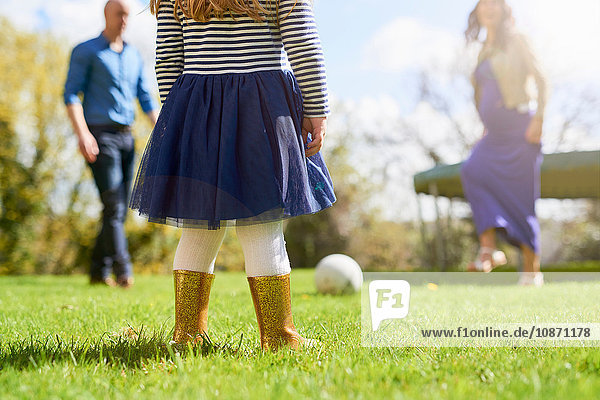Niederer Teil eines Mädchens im Garten mit Familie beim Fussballspielen