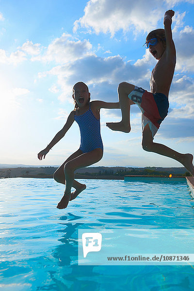 Mädchen und Bruder springen in den Swimmingpool  Buonconvento  Toskana  Italien