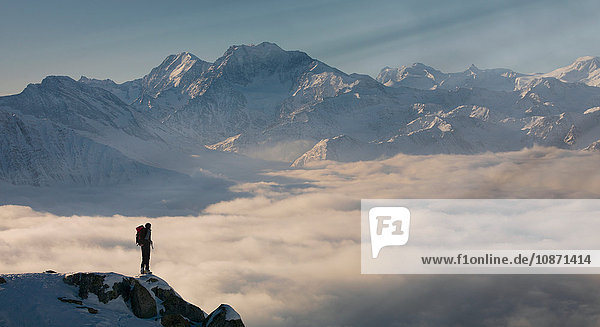 Bergsteiger auf einem Gipfel  der aus dem Nebel in den Alpen auftaucht  Bettmeralp  Wallis  Schweiz