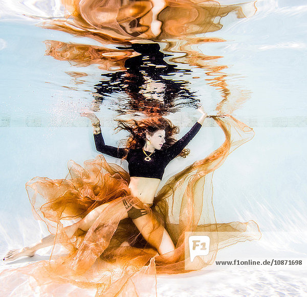 Frau in Schwarz posiert unter Wasser im Pool