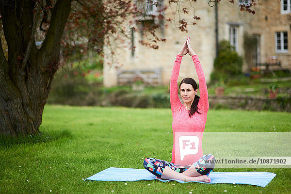 Schwangere Frau sitzt im Freien  in Yogastellung
