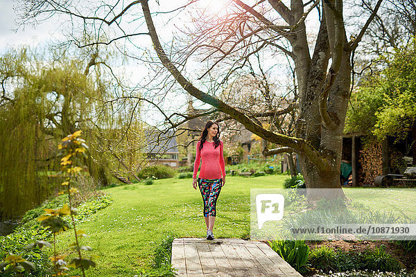 Schwangere Frau geht im Garten spazieren