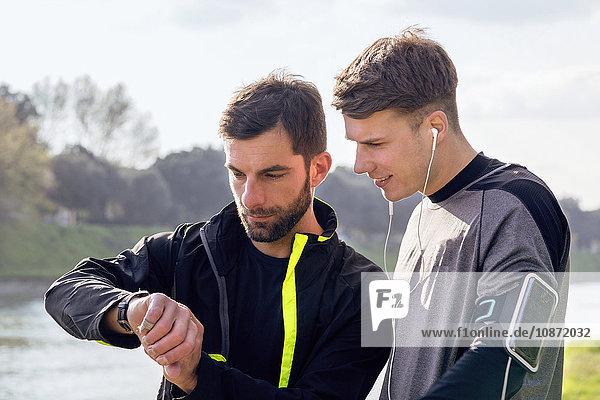 Two male friends outdoors  ready to work out  looking at activity tracker