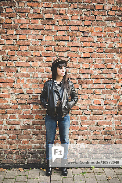 Young woman in front of brick wall