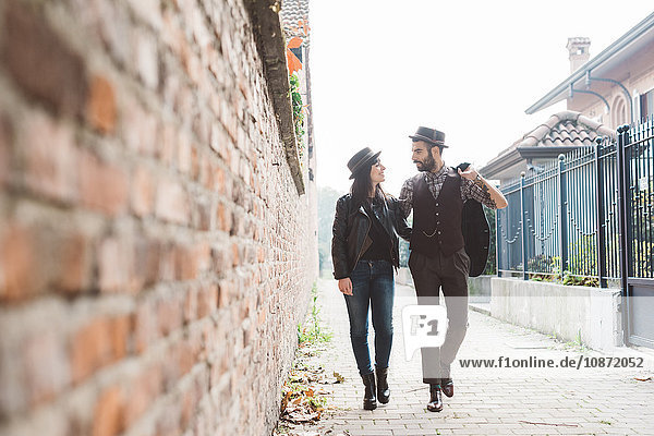 Young couple walking past brick wall