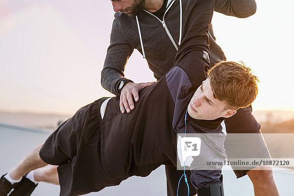 Mid adult man helping young man exercise