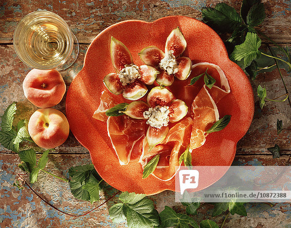 Essen im mediterranen Stil  Parmaschinken  Feigen  Weichkäse  Pfirsiche  ein Glas Weißwein  Draufsicht