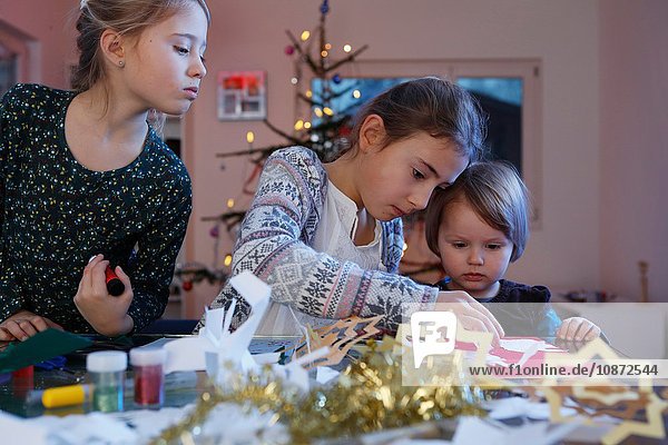 Mädchen bei Tisch beim Basteln von Weihnachtszeitungen