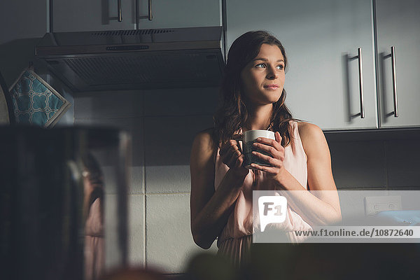Junge Frau macht in der Küche eine Kaffeepause