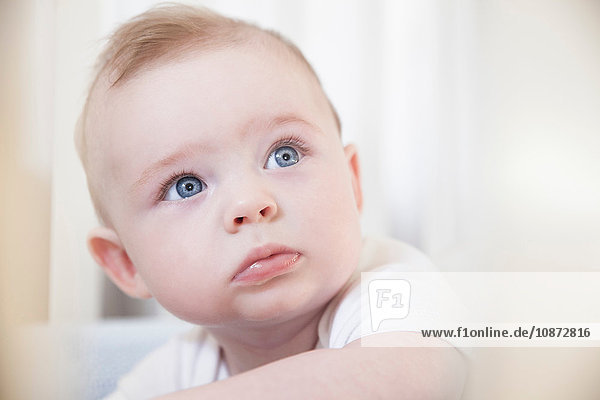 Portrait of blue eyed baby boy staring from crib