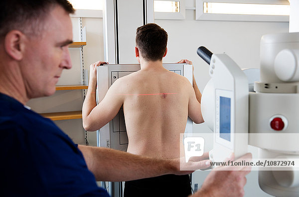 Doctor preparing equipment for x-ray scan on male patient