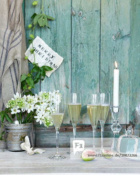 Champagner mit Weihnachtsgeschenk und angezündeter Kerze auf der Terrasse