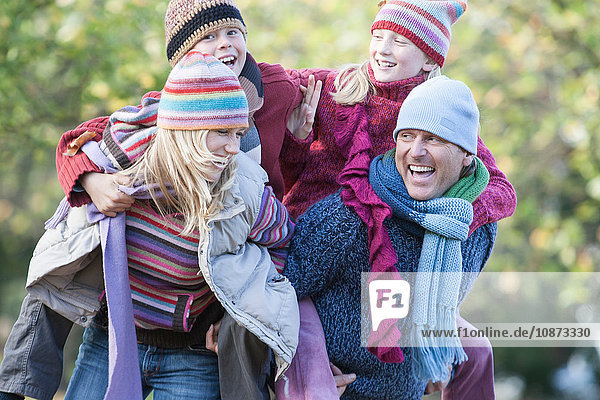 Family out together in park  mother and father carrying children on back  laughing