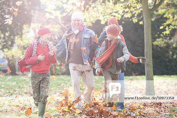 Family having fun in park  walking through autumn leaves