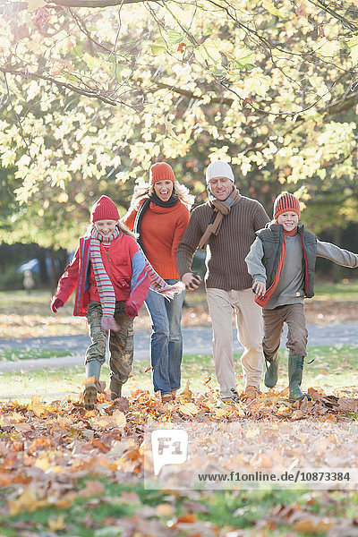 Family in park together  walking through autumn leaves