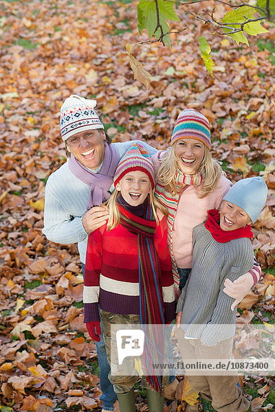 Portrait of family in park  surrounded by autumn leaves  smiling  elevated view