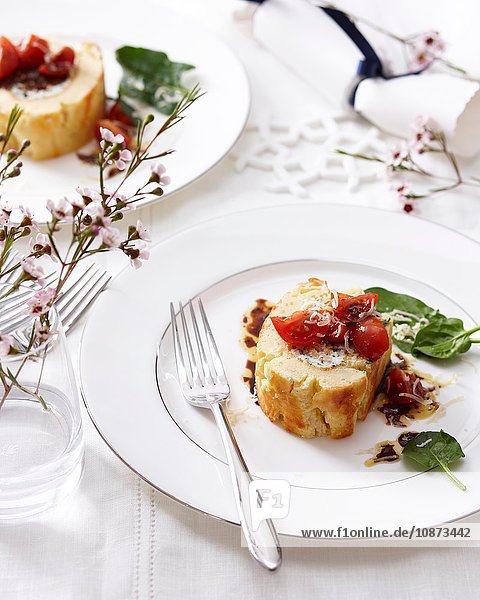 Hochwinkelansicht einer Ziegenkäse-Roulade mit Tomaten und Basilikum auf elegantem Teller