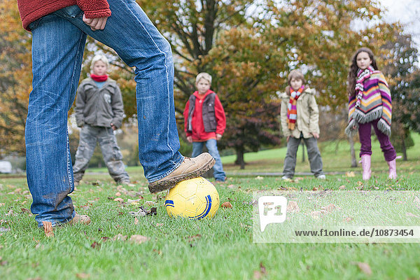 Vater und Kinder beim Fussballspielen im Park