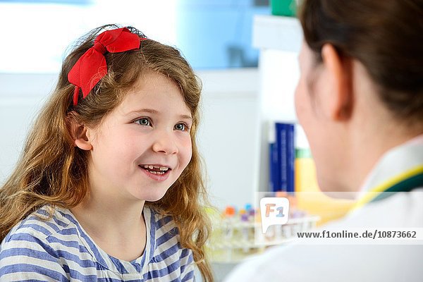 View over shoulder of girl consulting with doctor in clinic smiling