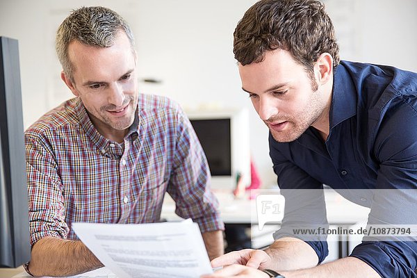 Colleagues in office discussing paperwork smiling