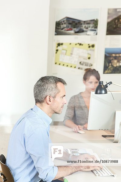View through glass  side view of mature man in office using computer